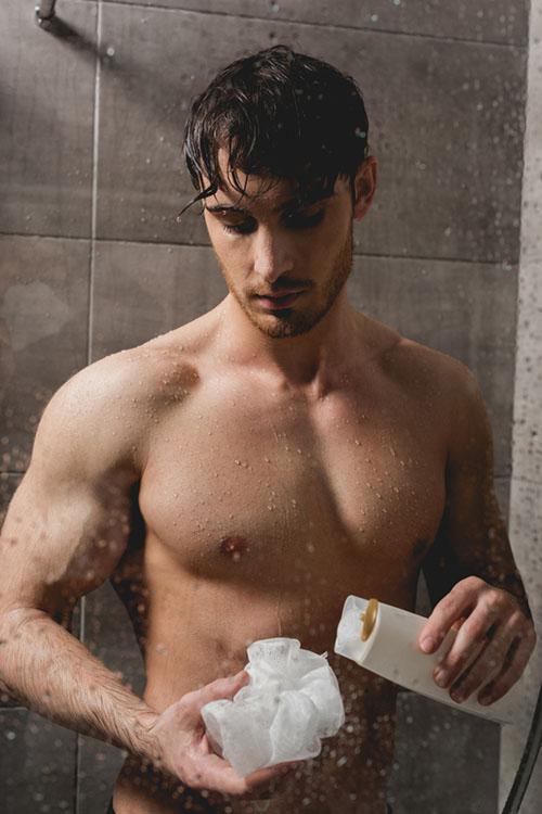 man holding loofah in shower